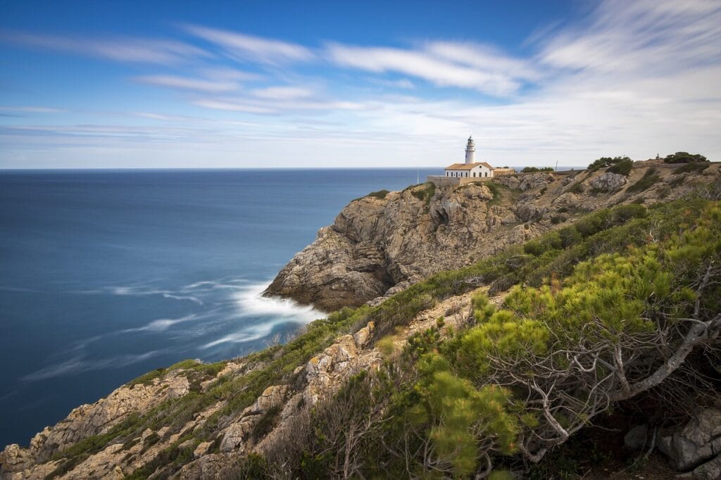Casita arriba de unas rocas sobre la playa, con vista hacia el océano azul y con un paisaje despejado.